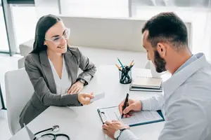 A doctor and a female patient are sitting at a desk and having a discussion.