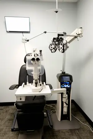 An eye examination chair with an eye testing machine and a monitor in a room
