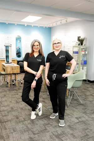 Two women in black uniforms standing in a room with furniture