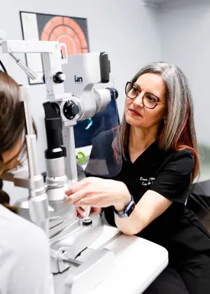 An optometrist is examining a patient's eyes with a phoropter.