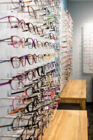 A display of glasses in a store with wooden benches and a blue wall in the background.