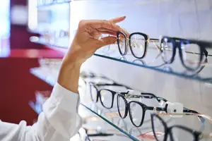 A person in a white shirt picking up a pair of eyeglasses