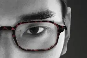 Close-up of a person's eye wearing glasses with a black and red frame