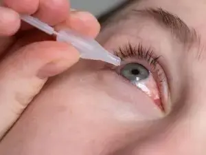 a person applying eye drops with a plastic dropper