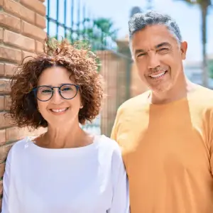 A smiling couple standing next to each other near a brick wall
