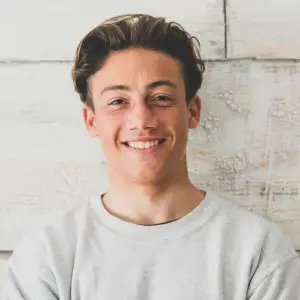 young man smiling in front of a textured white wall
