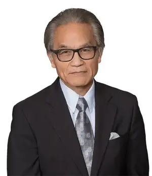A photo of an older man wearing a business suit, glasses, and a tie