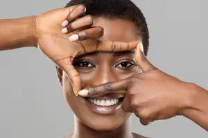 A smiling woman making a frame with her hands around her face