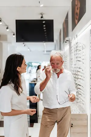 A man wearing glasses and talking to a woman in a shop
