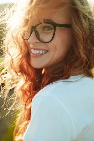 Portrait of a smiling woman with curly red hair and glasses