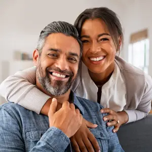 A smiling couple on a couch in a living room