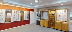 A room with a display of glasses and wooden cabinets, a white door, and a ceiling fan.