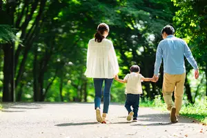 A family walking in a park with trees in the background
