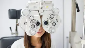 A woman is using an eye testing machine at an optometrist's office