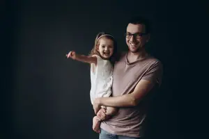 father wearing glasses holding little girl