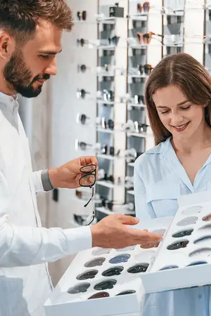 A man and a woman are looking at glasses in a box in a store