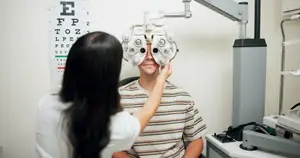 A woman adjusts a man's eyeglasses in an optometrist's office.