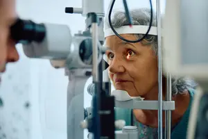 A woman with gray hair is undergoing an eye examination with an eye doctor.
