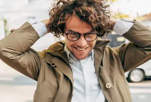 Man adjusting his curly hair with his hands while smiling