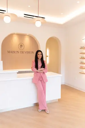 A woman in a pink suit is standing in front of the counter of Maison de Vision.