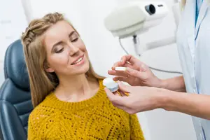 optometrist fitting woman with contact lenses