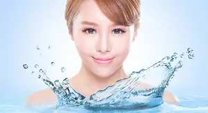 A woman with short red hair smiling and having water splash around her face