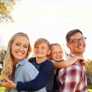A family of four, including two kids and two adults, posing for a picture in a park