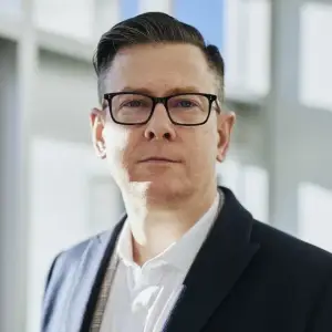 Man wearing glasses and a suit standing indoors