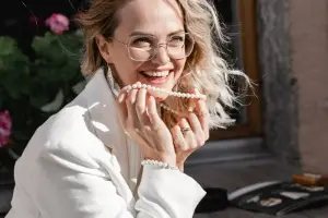 Blonde woman wearing white blazer and pearl necklace smiling at the camera