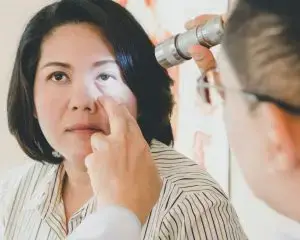 A woman is getting her eyes checked by a doctor in a clinic.