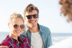 A man and a woman smiling at the camera at the beach
