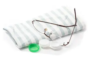 A pair of glasses, a contact lens case, and a blue and white striped cloth are displayed on a white background.