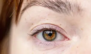 Close up of a woman's eye with brown iris and reflection of a window