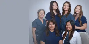 A group of women in blue uniforms are smiling and posing for a photograph.