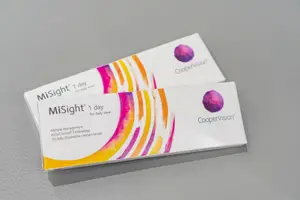Two MiSight 1-day contact lenses on a gray surface with colorful designs.