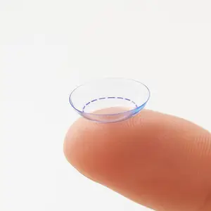 A finger is holding a clear circular object that is probably a contact lens.