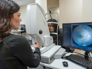 Woman checking the eye of another woman with an eye test machine