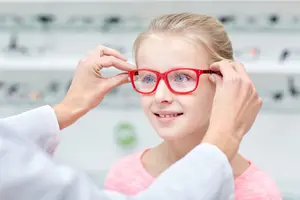 A young girl is having her glasses adjusted by a doctor in a clinic.