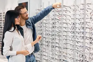 a man and woman choosing glasses in a store