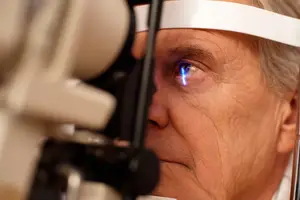 an elderly man having his eye examined with a blue light shining in his eye