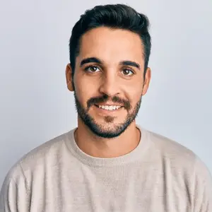 portrait of a smiling man with short hair and a beard wearing a beige sweater