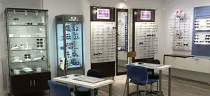 Inside a store with glasses on display and tables with chairs.