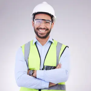 A man in a white helmet and green vest is smiling and posing for a photo.