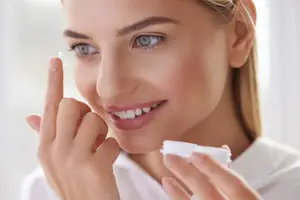 A woman is putting in contact lenses into her eyes