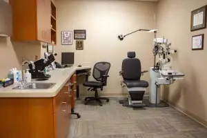An examination room with a desk, a monitor, a sink, and various medical equipment