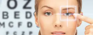 woman pointing to her eye while looking at an eye chart