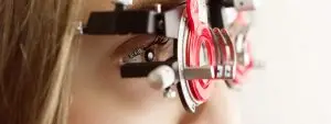 Close-up of a woman's eye wearing a red-framed eyeglass with a black lense and a silver dial on the right side