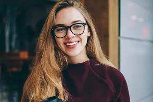 Woman with glasses and a maroon top smiling at the camera