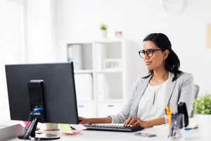 A woman is typing on a computer in an office