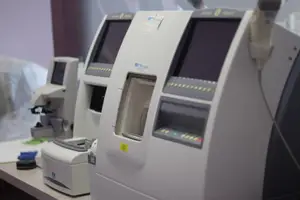 Multiple medical devices, including monitors and a scanner, are positioned on a table in a laboratory setting.